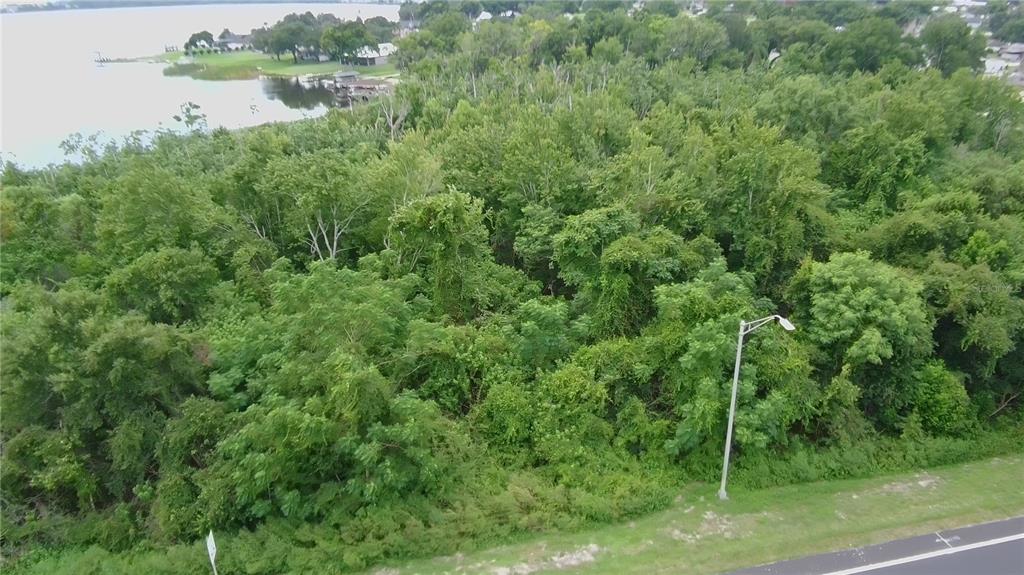 An aerial view shows a wooded lot situated between a highway and a lake — 0 ALFRED DRIVE E, LAKE ALFRED, FL