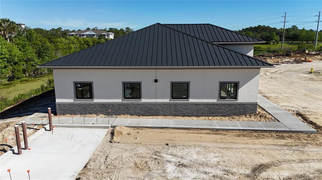 An exterior view of a single-story building with a dark metal roof and stone siding — 60 EXCHANGE LOOP LOOP UNIT 4, PALM COAST, FL