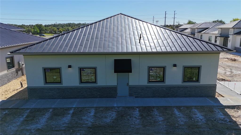 An exterior view of a single-story building with a metal roof and brick base — 60 EXCHANGE LOOP LOOP UNIT 4, PALM COAST, FL