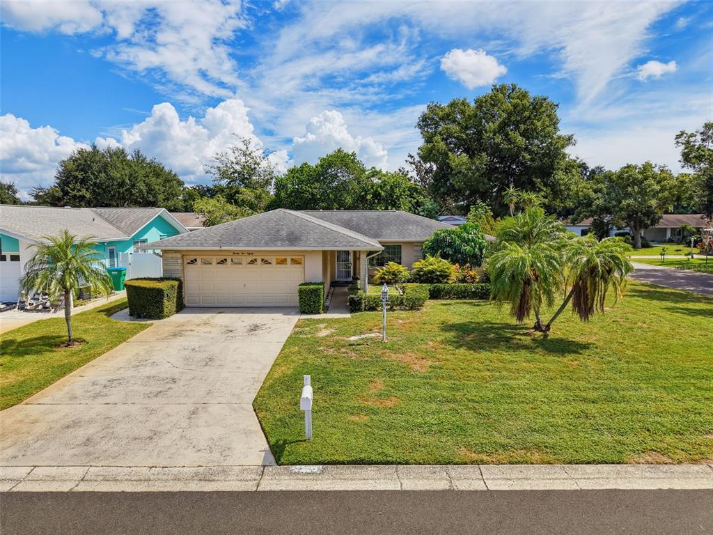 A single-story house with a beige garage, a concrete driveway, and palm trees in the yard — 2580 WINDWOOD DRIVE, CLEARWATER, FL