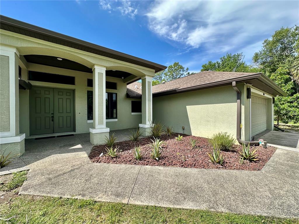 A wooden swing set sits under a large oak tree beside a black fence — 7759 ESTATES DRIVE, NORTH PORT, FL