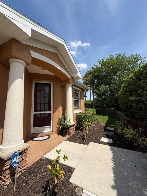 A tan house exterior features a front door with a screen, columns, and a walkway — 11505 52ND COURT E, PARRISH, FL