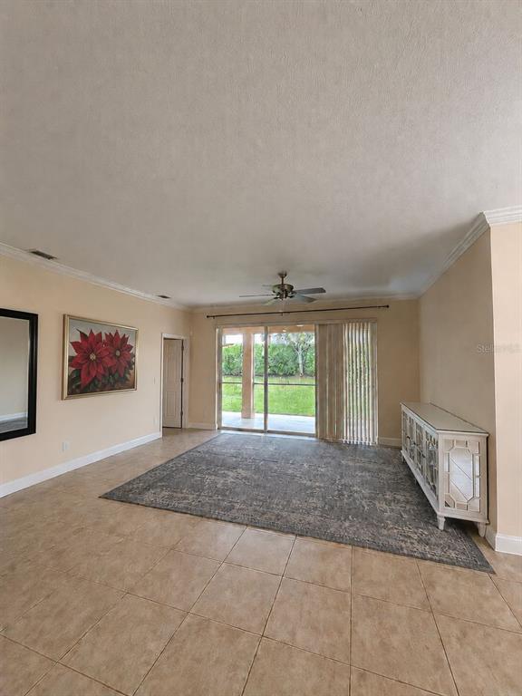 A living room with tile flooring, a large area rug, and sliding glass patio doors — 11505 52ND COURT E, PARRISH, FL
