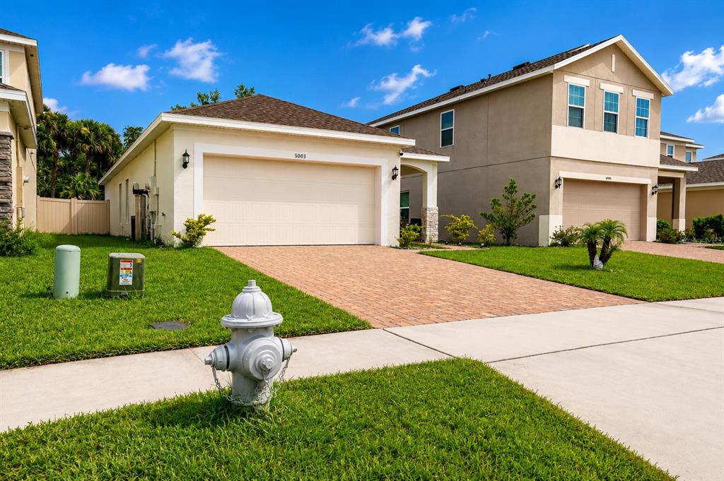 A kitchen features white cabinets, granite countertops, a stainless steel refrigerator, and a herringbone backsplash — 5003 ROYAL POINT AVENUE, KISSIMMEE, FL