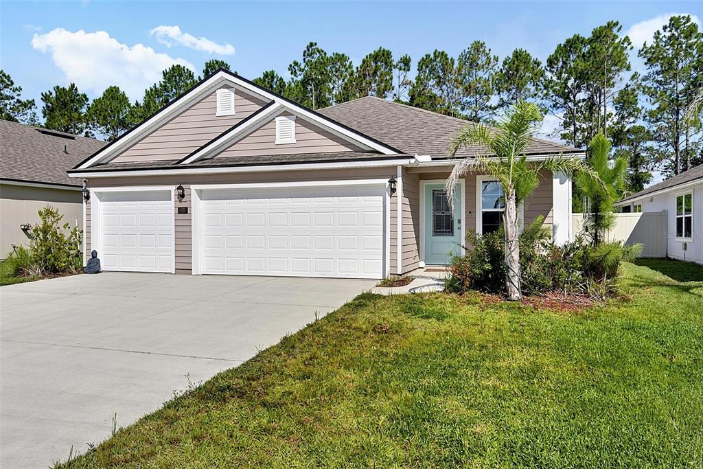 A single-story suburban house with a two-car garage, light blue front door, and palm tree — 425 NARVAREZ AVENUE, ST AUGUSTINE, FL