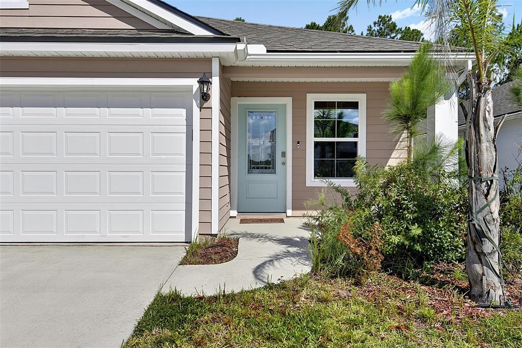 The exterior of a house features a light blue front door, a garage, and landscaping — 425 NARVAREZ AVENUE, ST AUGUSTINE, FL