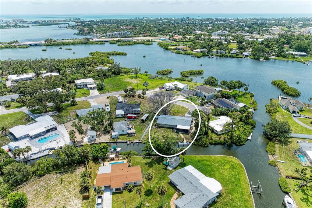 An aerial view shows a single-story house circled on a waterfront lot with trees — 302 DONA DRIVE, NOKOMIS, FL