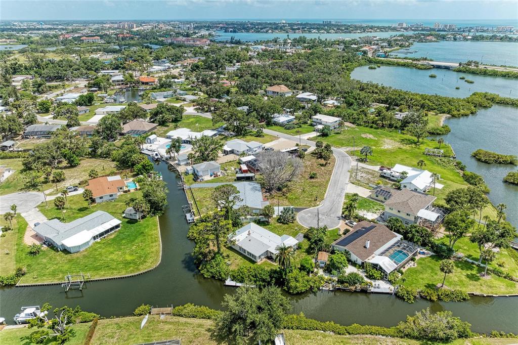 An aerial view shows residential houses situated along a canal near a large bay — 302 DONA DRIVE, NOKOMIS, FL