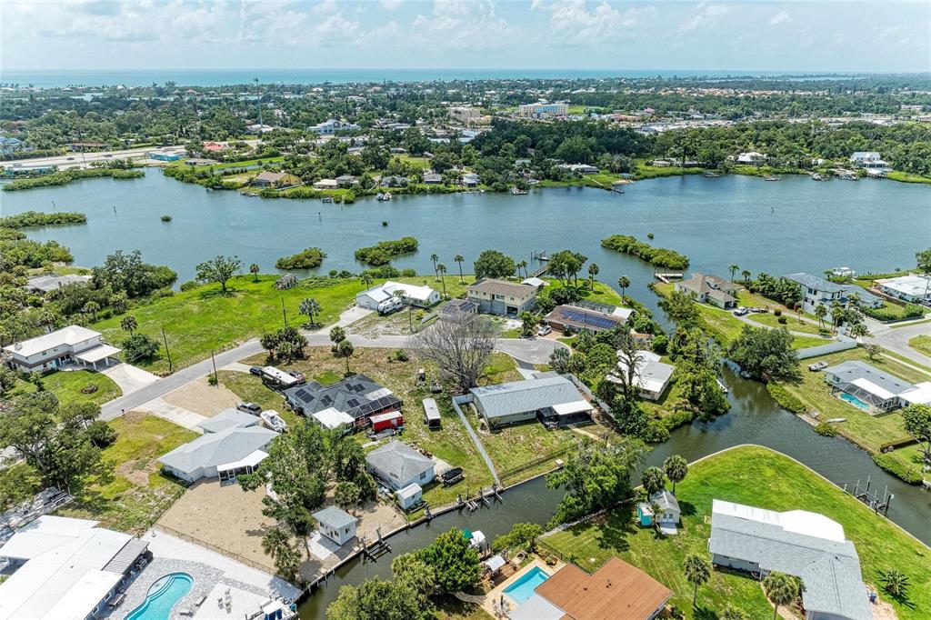 An aerial view shows several houses situated along a canal leading to a large bay — 302 DONA DRIVE, NOKOMIS, FL