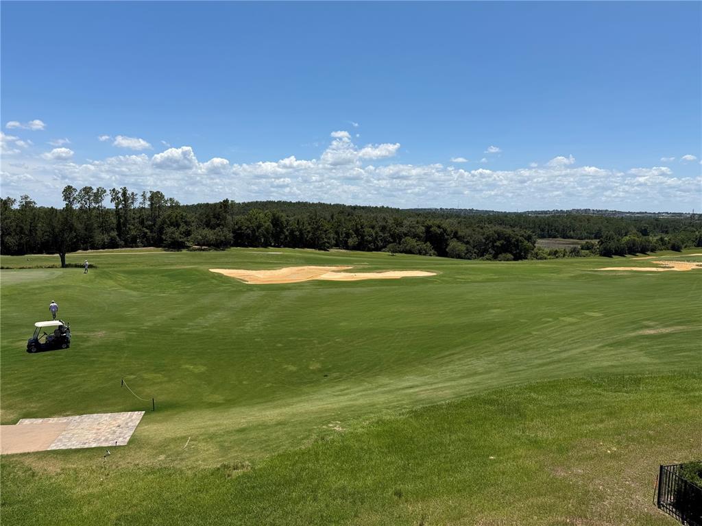 A view of a golf course fairway with sand bunkers, trees, and a golf cart — 16038 VETTA DRIVE, MONTVERDE, FL