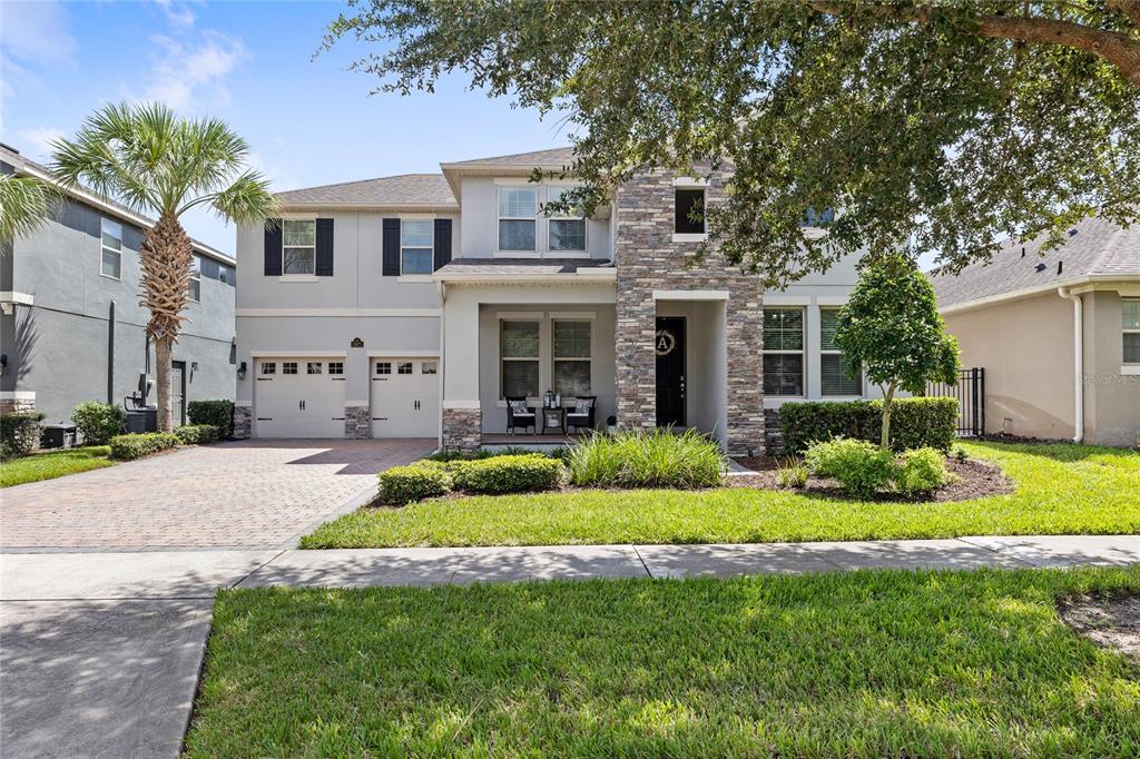 A two-story suburban house with a stone facade, a two-car garage, and a paved driveway — 15671 MARINA BAY DRIVE, WINTER GARDEN, FL