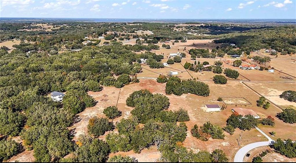 An aerial view shows a rural landscape with scattered houses, trees, and open fields — SWEETWOOD LANE, CLERMONT, FL