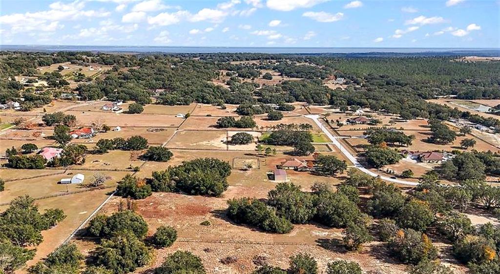 An aerial view shows a rural landscape with scattered houses, fenced pastures, and wooded areas — SWEETWOOD LANE, CLERMONT, FL