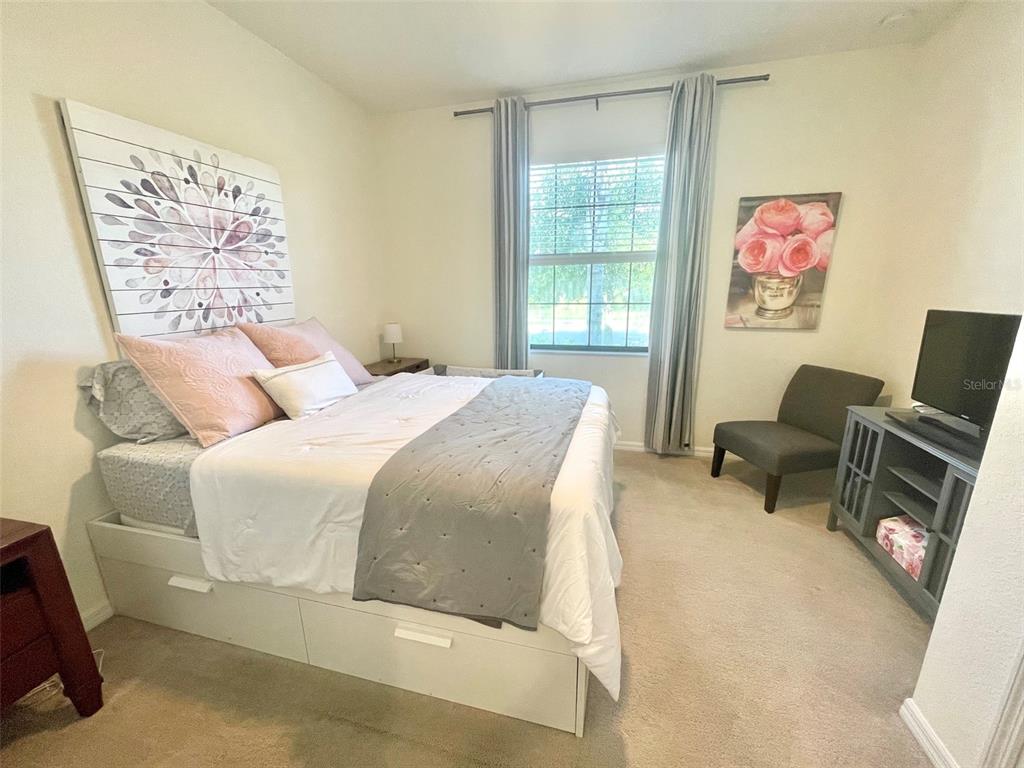A bedroom features a bed with storage drawers, a gray chair, and a television stand — 531 FIRE BUSH COURT, BRADENTON, FL
