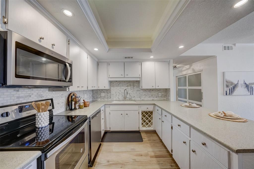 A white kitchen features stainless steel appliances, light countertops, and a subway tile backsplash — 6 BELLEVIEW BOULEVARD UNIT 101, BELLEAIR, FL