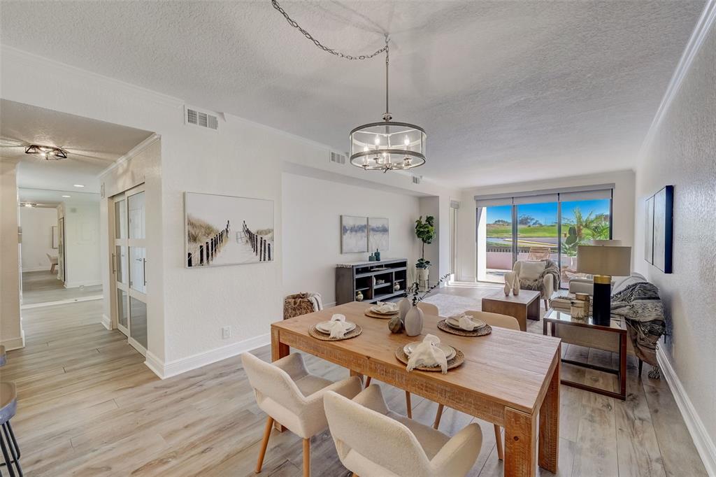 A dining area and living room with wood-look flooring, a chandelier, and sliding glass doors — 6 BELLEVIEW BOULEVARD UNIT 101, BELLEAIR, FL