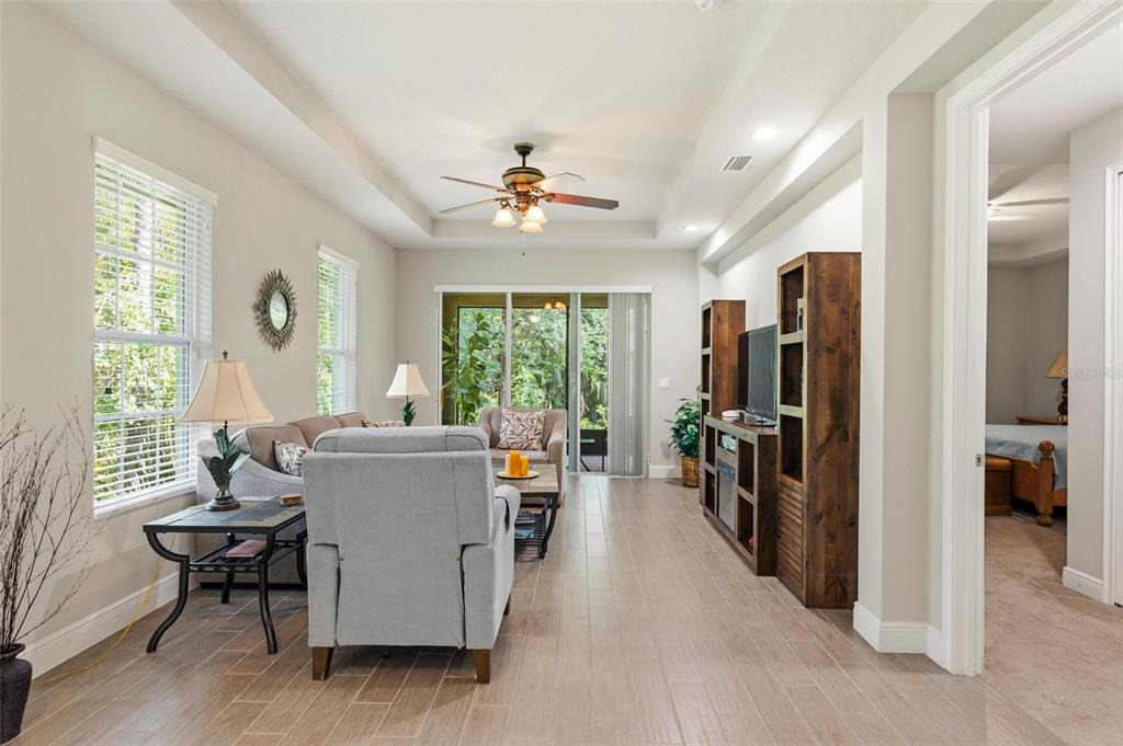 A living room features light tile floors, a ceiling fan, and a wooden media console — 46 HERON WING DRIVE, ORMOND BEACH, FL