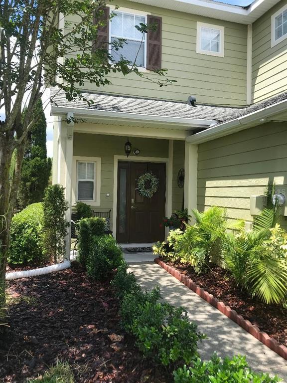 A light green two-story house features a covered entryway with a dark brown front door — 8524 SANDPIPER RIDGE AVENUE, TAMPA, FL