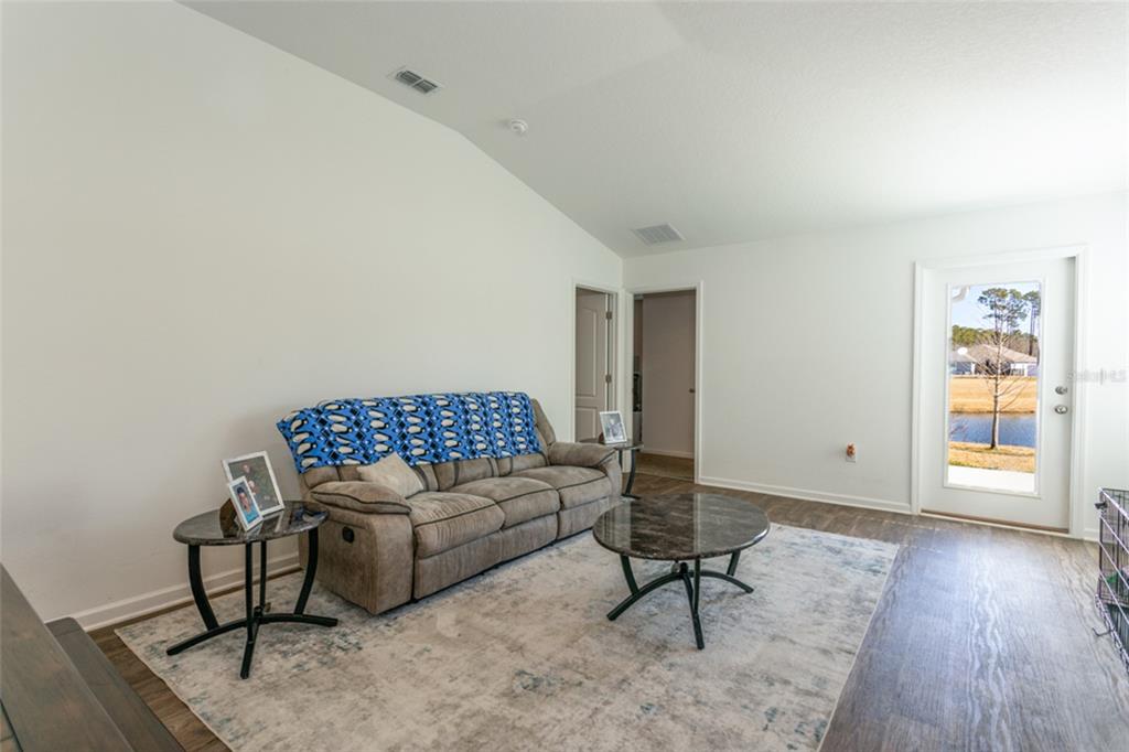 A living room features a tan sofa, a marble coffee table, and a glass-paned exterior door — 18 BOGEY PLACE, BUNNELL, FL