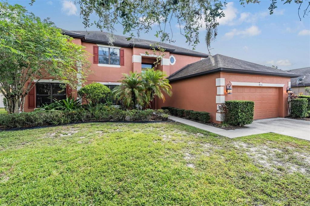 A two-story house with a terracotta exterior, a two-car garage, and a landscaped front yard — 456 OAK LANDING BOULEVARD, MULBERRY, FL