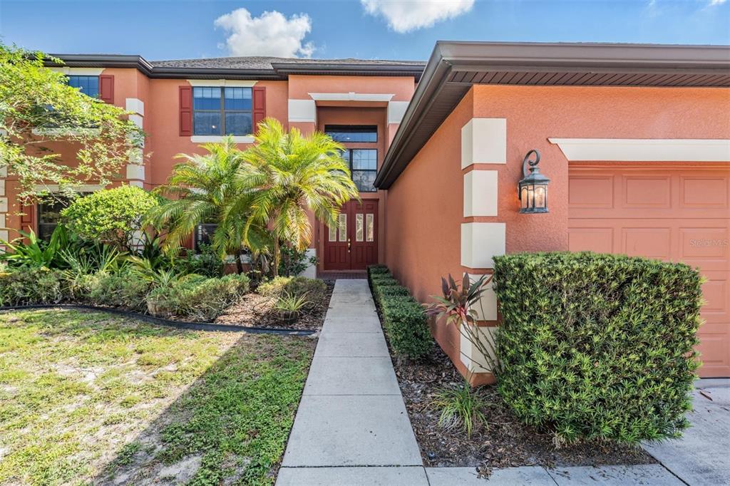 A two-story orange stucco house features a front walkway, a palm tree, and a garage — 456 OAK LANDING BOULEVARD, MULBERRY, FL
