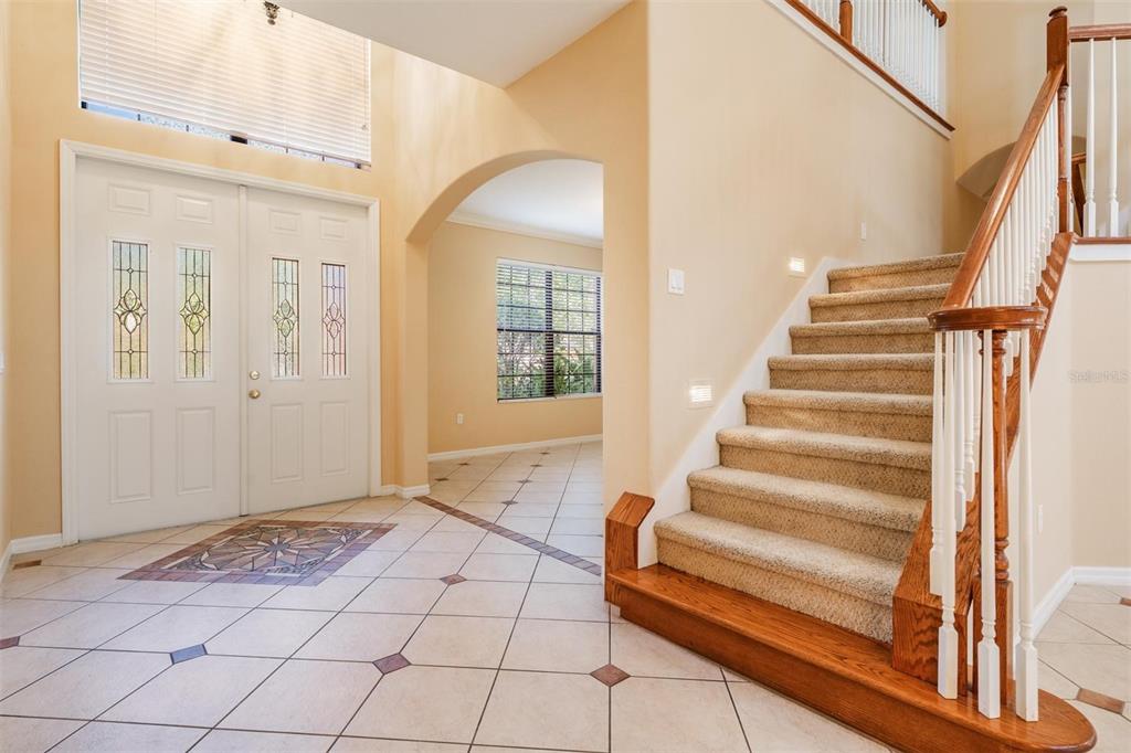A foyer features tiled floors, a carpeted staircase with a wooden railing, and double entry doors — 456 OAK LANDING BOULEVARD, MULBERRY, FL