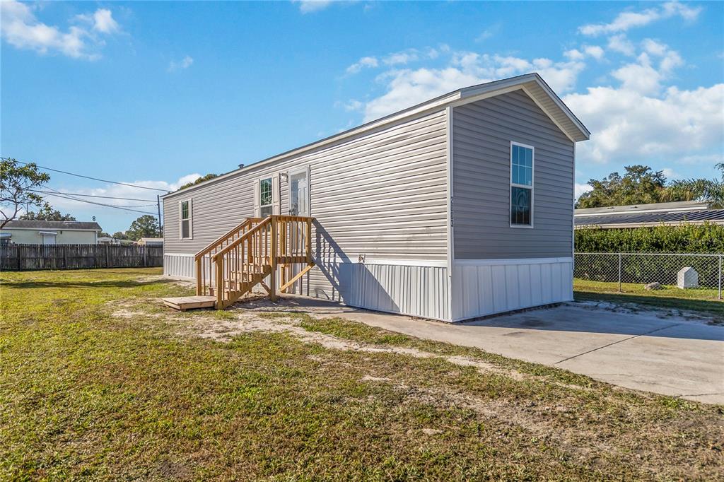 A single-story manufactured home with gray vinyl siding and a wooden staircase entrance — 2003 OAK STREET, ST CLOUD, FL
