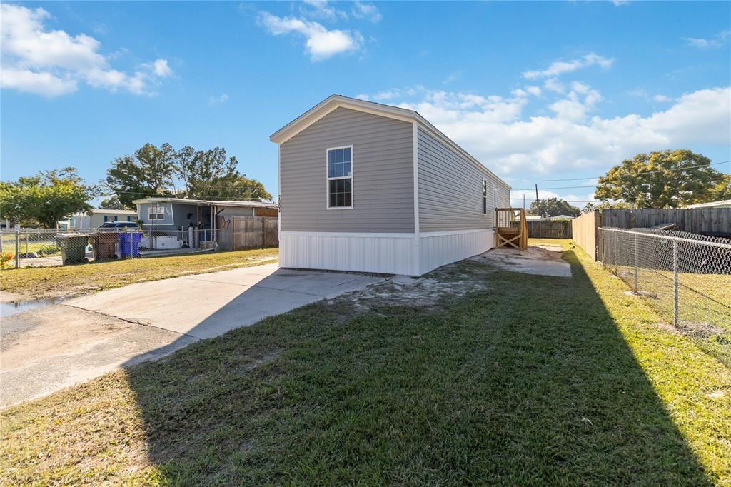 A gray mobile home with white skirting sits on a lot with a concrete driveway — 2003 OAK STREET, ST CLOUD, FL