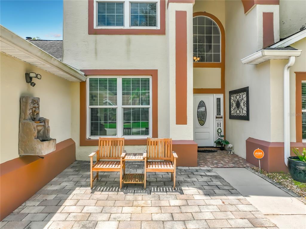 A paved patio features two wooden chairs and a stone fountain in front of a house — 1756 BRANCHWATER TRAIL, ORLANDO, FL
