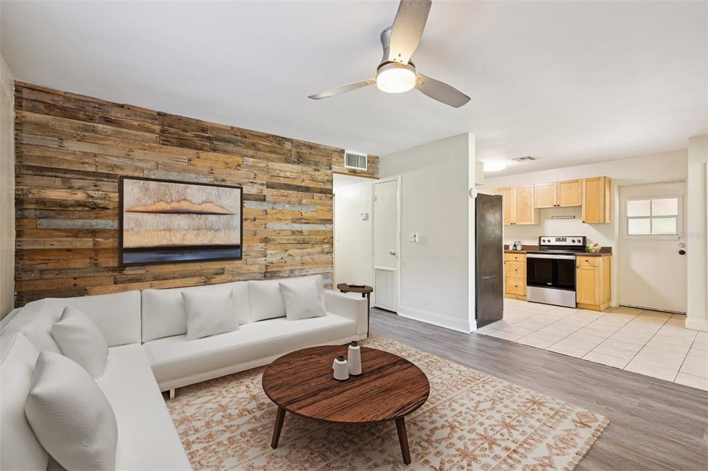 A living room with a wood-plank accent wall, white sectional sofa, and adjacent kitchen area — 509 HILLSIDE AVENUE, ORLANDO, FL