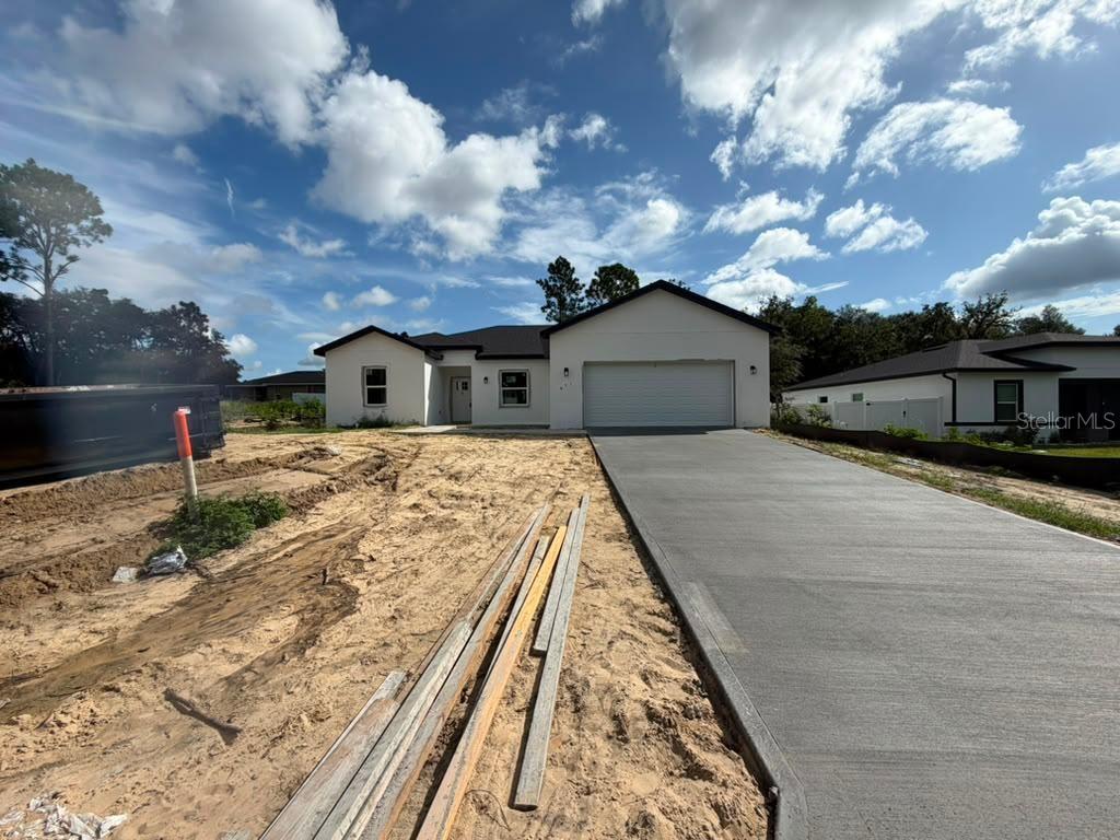 A newly constructed single-story house features a white exterior, a two-car garage, and a concrete driveway — 671 MARION OAKS MANOR, OCALA, FL