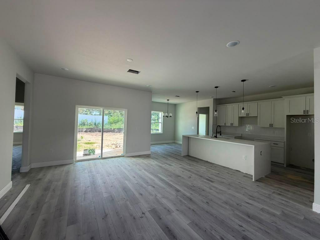 An open-concept kitchen and living area with light gray wood-look flooring and white cabinetry — 671 MARION OAKS MANOR, OCALA, FL