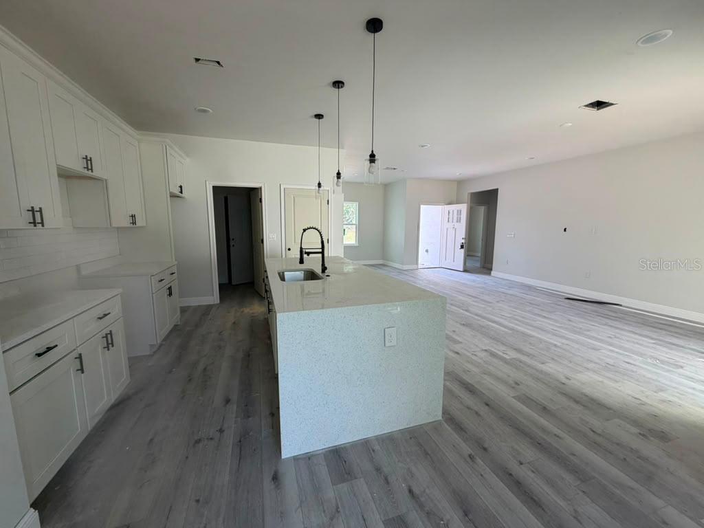 A kitchen with white cabinets, a quartz island, and light wood-look flooring — 671 MARION OAKS MANOR, OCALA, FL