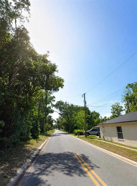 A paved road stretches into the distance, flanked by trees and a single-story house — 0 BUNGALOW BOULEVARD, SANFORD, FL