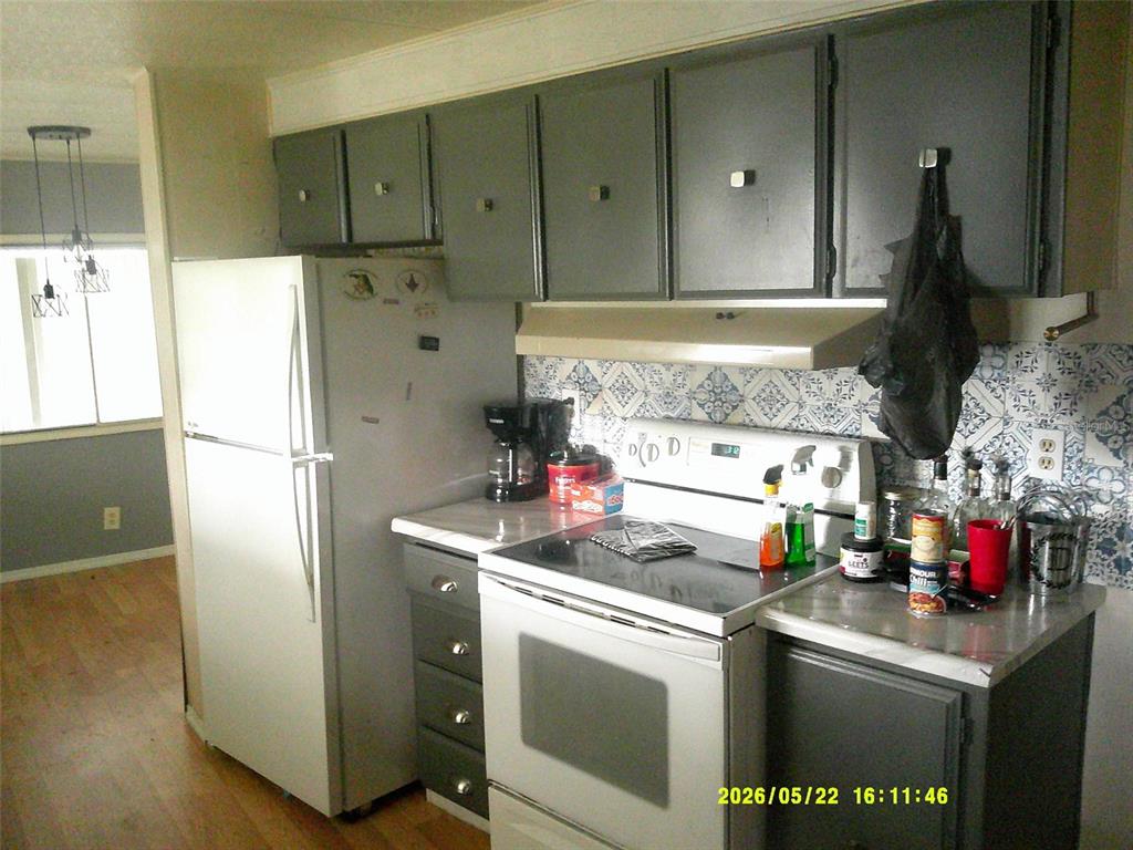 A kitchen features gray cabinets, white appliances, and a patterned blue and white backsplash — 15211 SE 104TH COURT, SUMMERFIELD, FL