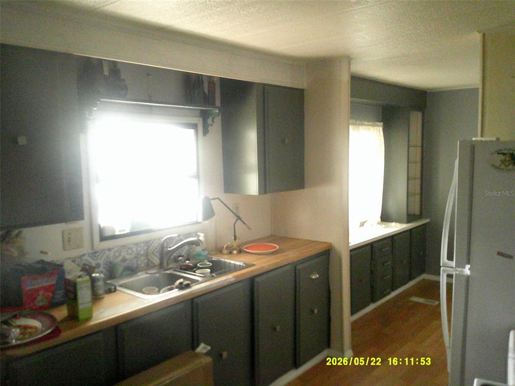 A kitchen features dark gray cabinets, a wood countertop, a stainless steel sink, and appliances — 15211 SE 104TH COURT, SUMMERFIELD, FL