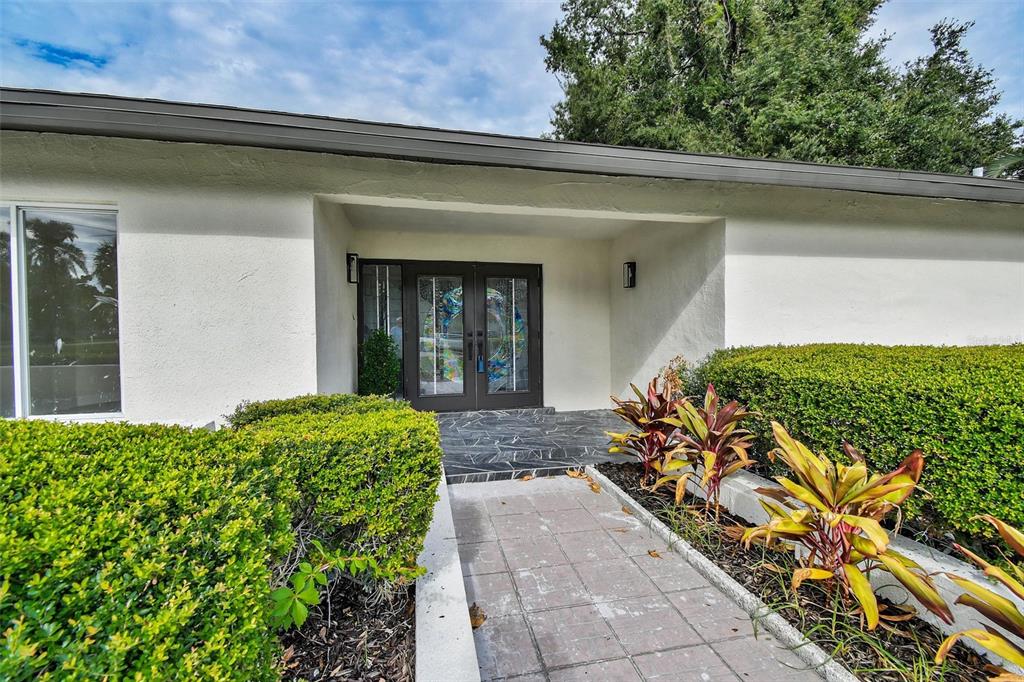 A living room features a marble fireplace, vertical wood slats, gray armchairs, and a sectional sofa — 207 DUNBRIDGE DRIVE, PALM HARBOR, FL