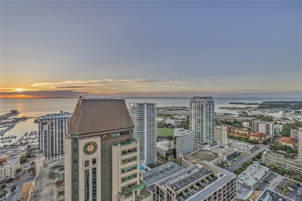 An aerial view shows a city skyline with high-rise buildings near a bay at sunset — 275 1ST AVENUE S UNIT 3704, ST PETERSBURG, FL