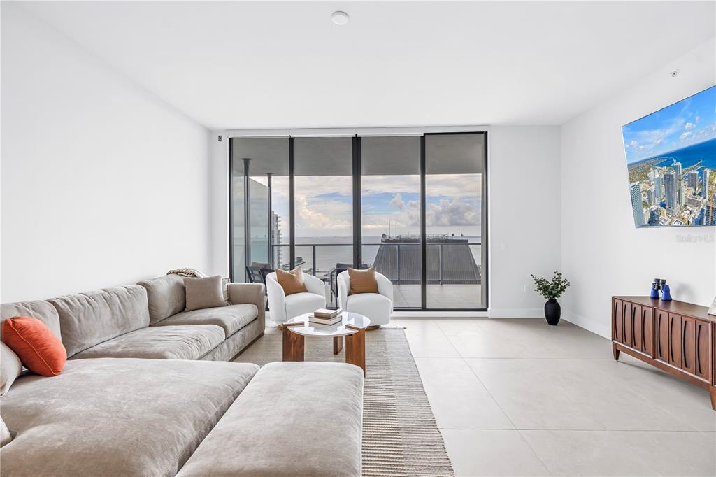A modern living room features a large sectional sofa, two armchairs, and floor-to-ceiling windows — 275 1ST AVENUE S UNIT 3704, ST PETERSBURG, FL