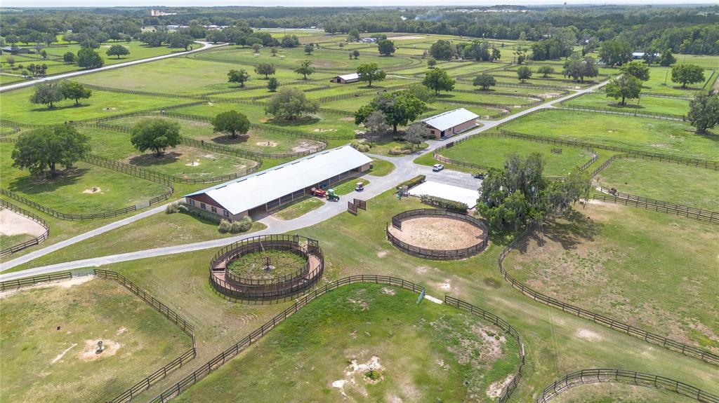 An aerial view shows a horse farm with stables, round pens, and fenced pastures — 5100 W HWY 329, REDDICK, FL
