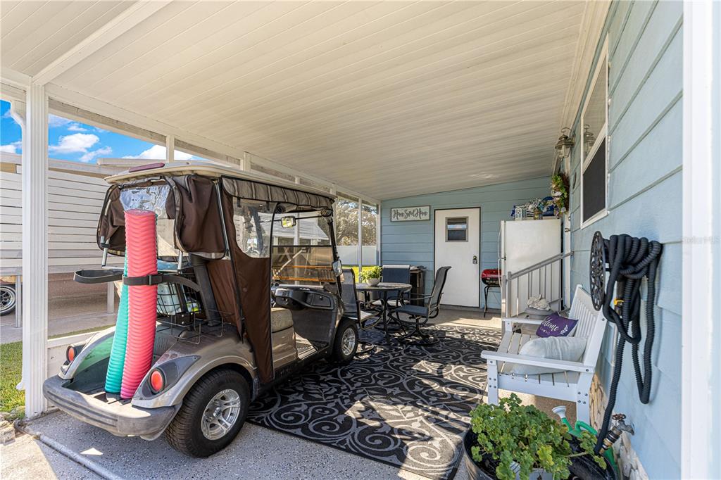 A covered patio features a golf cart, outdoor dining set, white bench, and patterned rug — 606 TARRSON BOULEVARD, LADY LAKE, FL