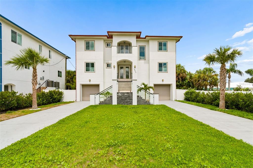 A three-story white house with two garages, a central staircase, and two palm trees — 1964 CEDAR DRIVE, DUNEDIN, FL