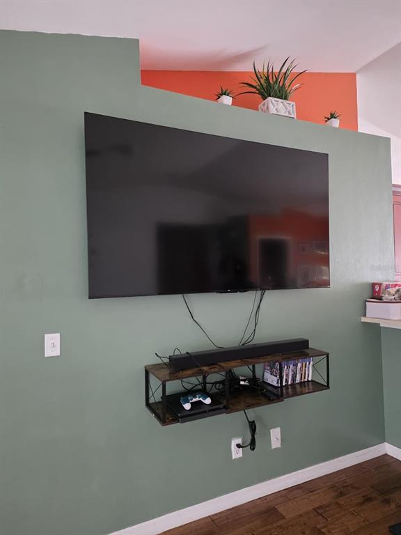 A wall-mounted television and floating shelf are centered on a sage green accent wall — 3529 SUNSHINE BOULEVARD, LEHIGH ACRES, FL