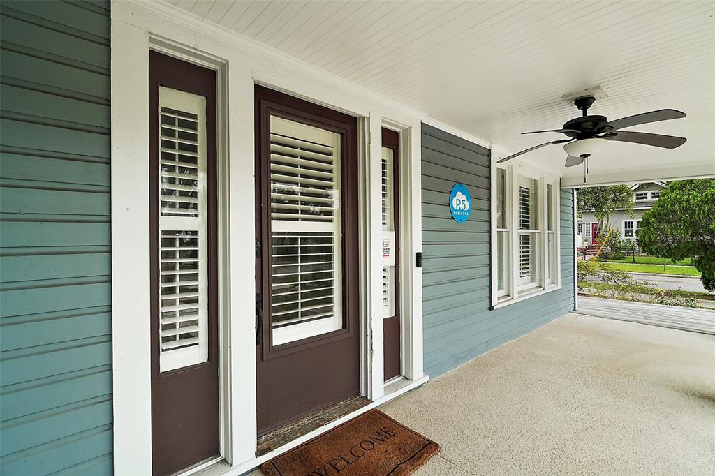 A covered front porch features blue siding, a ceiling fan, and a brown front door — 427 S GROVE STREET, EUSTIS, FL