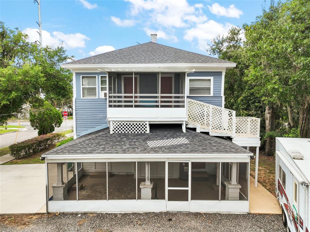 A two-story blue house features a large screened-in ground floor porch and an upper balcony — 427 S GROVE STREET, EUSTIS, FL