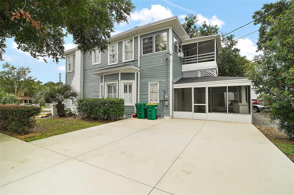 A two-story blue house with a concrete driveway, screened-in porch, and two trash bins — 427 S GROVE STREET, EUSTIS, FL
