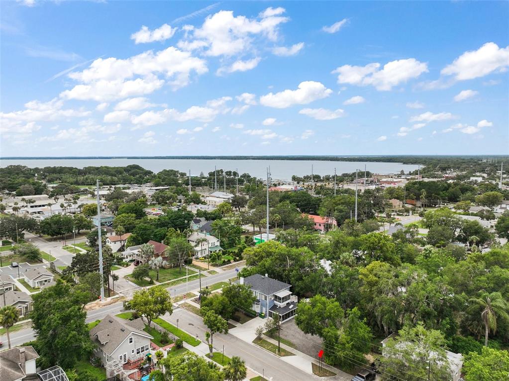 An aerial view shows a residential neighborhood with houses, trees, and a distant lake — 427 S GROVE STREET, EUSTIS, FL