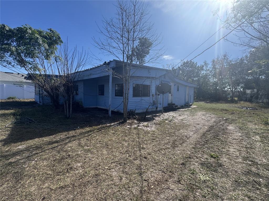 A light blue, single-story house with a metal roof sits on a dry, grassy lot — 11606 HUGGINS STREET, LEESBURG, FL