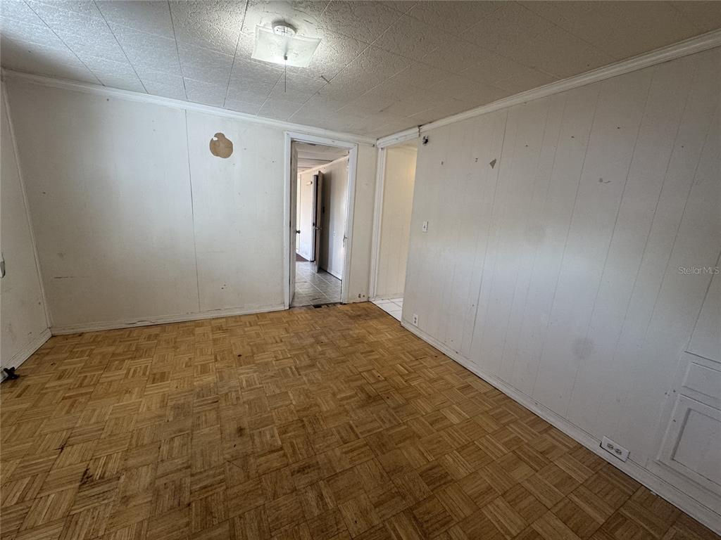 An empty room features wood parquet flooring, white paneled walls, and a ceiling light fixture — 11606 HUGGINS STREET, LEESBURG, FL