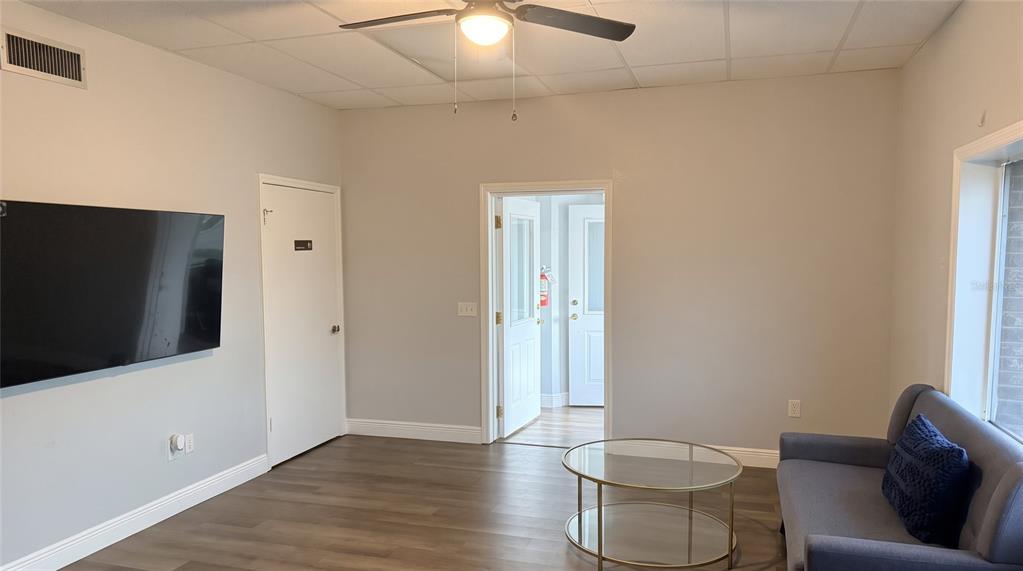 A kitchen area with white cabinets, a dark blue accent wall, and a wall-mounted television — 223 COMMONWEALTH AVENUE SW, POLK CITY, FL